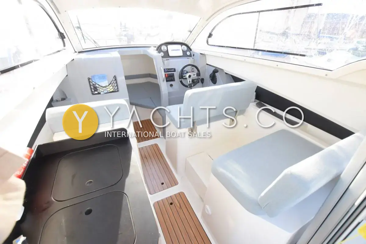 Quicksilver Activ 705: wheelhouse looking forward to the helm, with light blue seating, galley worktop and teak-effect floor inserts