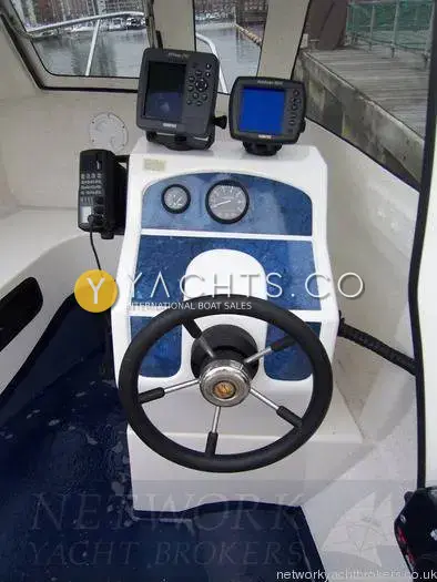 Raider 18: helm console with blue-panelled dash, two displays and VHF, marina visible through the windscreen