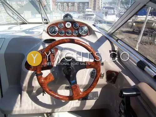 Regal 2460 Commodore: helm with burr wood-effect steering wheel and wood-trimmed dash of round gauges, marina behind