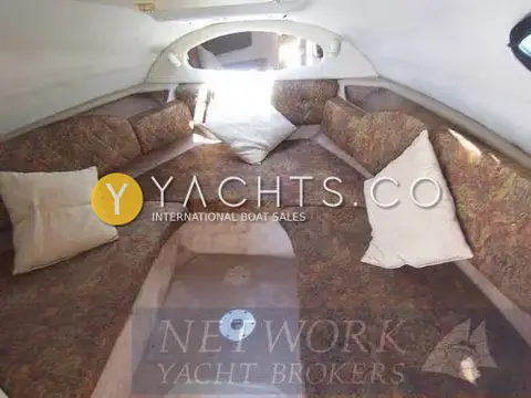 Regal 2460 Commodore: forward cabin V-berth seating in patterned upholstery with cream cushions and table base