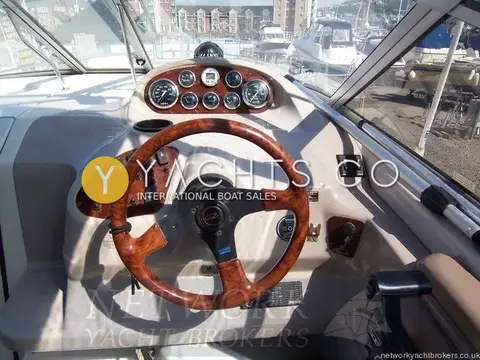 Regal 2460 Commodore: close view of helm dash with gauges, wood-trimmed switch panel and throttle lever