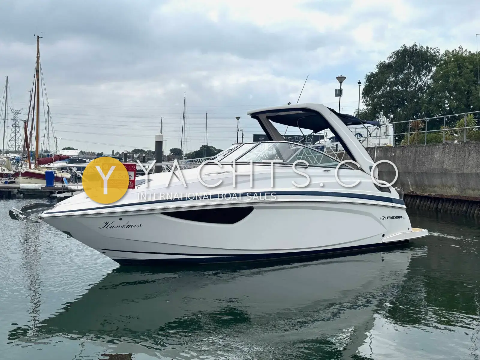 Regal 28 Express: white hull with dark blue stripe and radar arch, moored in a marina, seen from the bow quarter