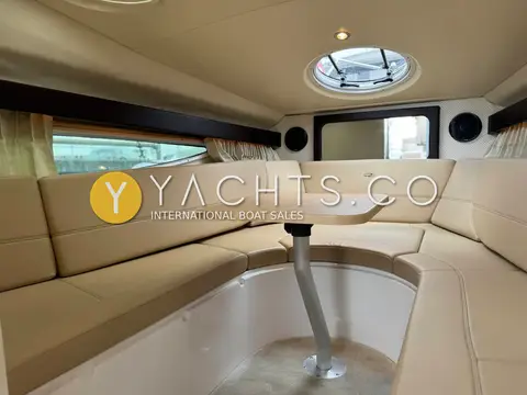Regal 28 Express: saloon with cream U-shaped leatherette seating around a pedestal table, overhead hatch and porthole