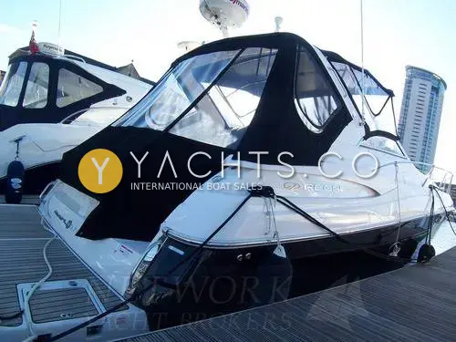 Regal 3760: stern quarter at a marina berth with black canopy fitted and tall tower behind