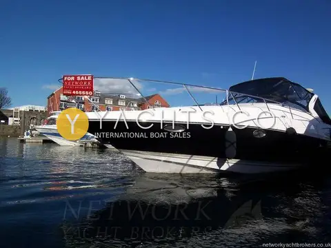 Regal 3760: dark hull and white superstructure seen from the water beside a marina wall