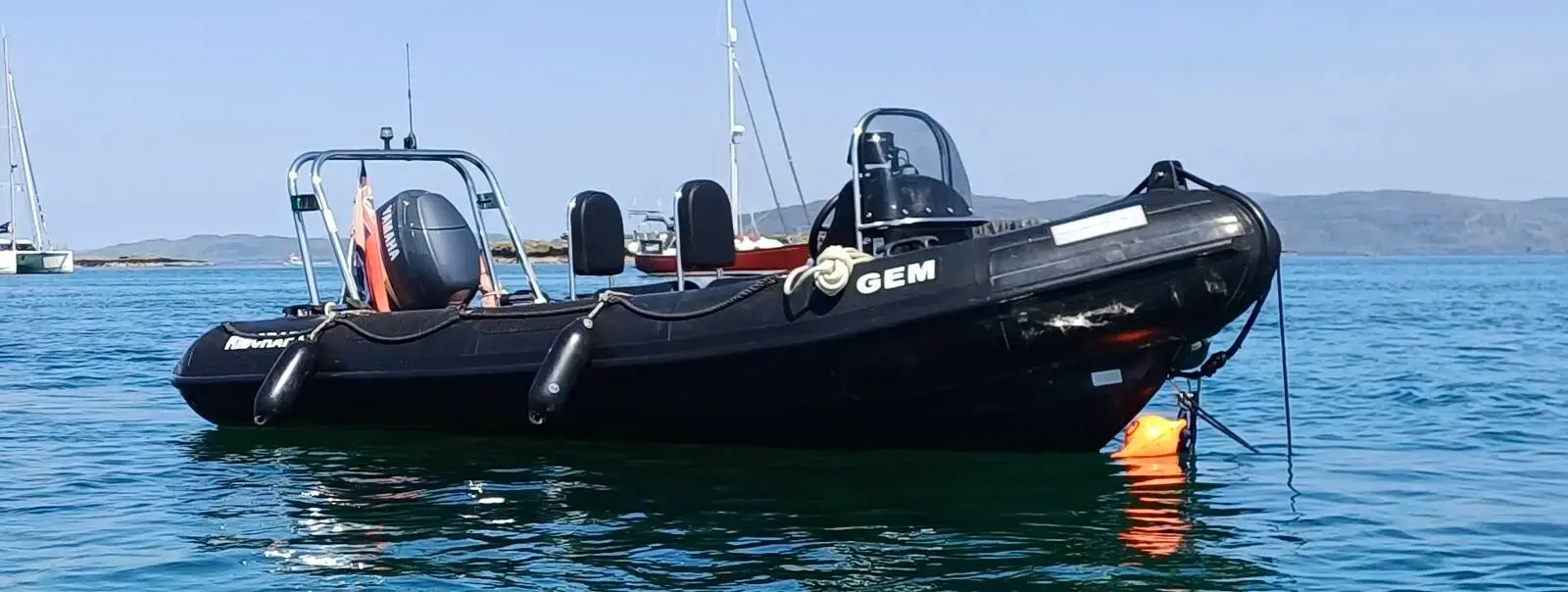 Ribcraft 5 M: black RIB with black tubes and stainless A-frame afloat at anchor in calm water