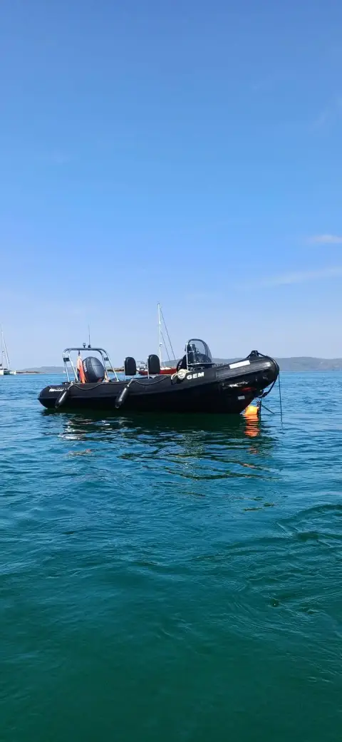Ribcraft 5 M: black RIB at anchor on clear green water under a blue sky