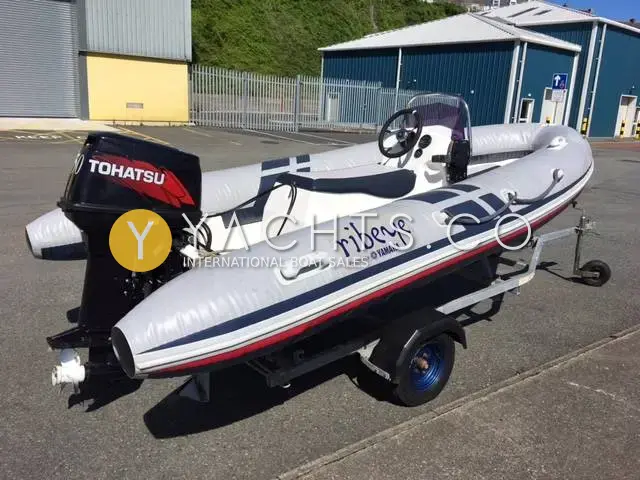 Ribeye 400: rIB on road trailer in a boatyard, Tohatsu outboard and console with windscreen visible