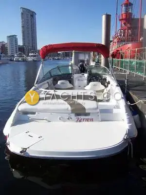 Rinker 192 Reduced: stern view showing the bathing platform, sun lounger and red bimini in a marina
