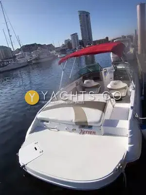 Rinker 192 Reduced: stern and aft sun lounger from the quarter, with red bimini and marina tower behind