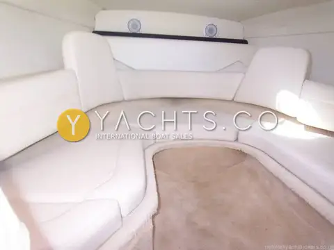 Rinker 210 MTX: forward cabin with cream U-shaped upholstered seating, carpeted floor and two speakers