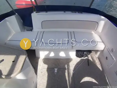 Rinker 230: aft cockpit bench seating in white with navy piping, carpeted floor and canopy