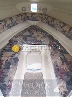 Rinker 232: cuddy cabin with patterned upholstery, overhead hatch and portable toilet in the floor well