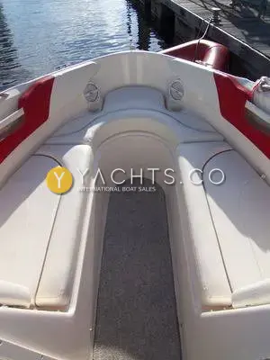 Rinker 232: bow seating area with cream upholstery, red side panels, speakers and grey carpeted footwell