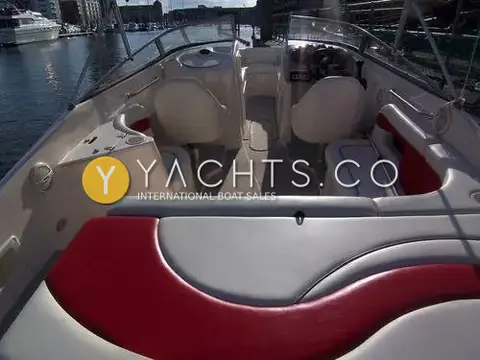 Rinker 232: cockpit view forward from the red and grey rear bench to the helm and walk-through windscreen