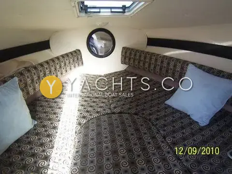 Rinker 232: forward cabin V-berth with patterned upholstery, blue cushions and overhead hatch