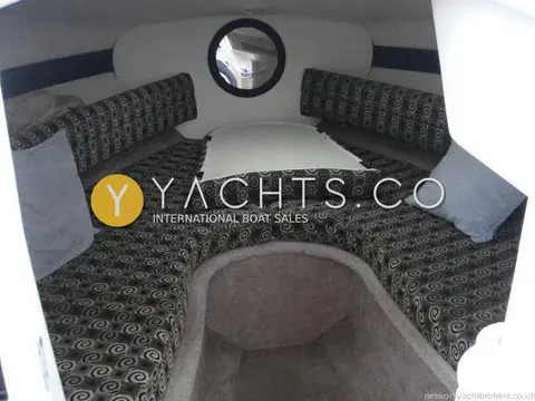Rinker 232: forward cuddy cabin with table insert in place among patterned seating