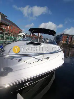 Rinker 232: white bow and foredeck with hatch and stainless rail, black Bimini, moored in a marina