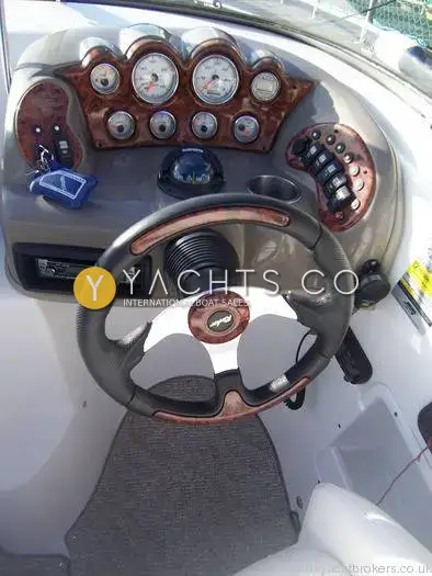 Rinker 232: helm station with sports steering wheel, wood-effect dash, compass, switches and stereo