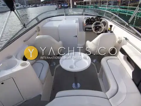 Rinker 232: cockpit looking forward to the helm, with two white bucket seats, pedestal table and walk-thru windscreen