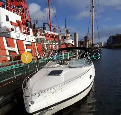 Rinker 232: bow quarter view of the white hull moored beside a red lightship in Swansea marina