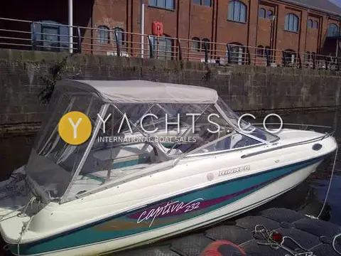 Rinker 232: starboard side with full camper canopy fitted, moored against a brick quay wall
