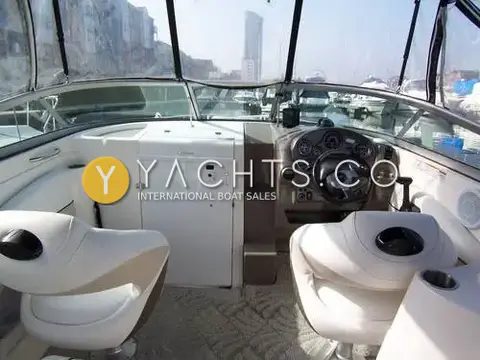 Rinker 246: cockpit looking forward to the helm and two white bucket seats under the canopy