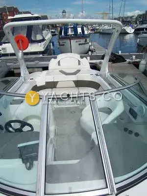 Rinker 262: view aft through the windscreen over the cockpit, white arch and marina berths behind