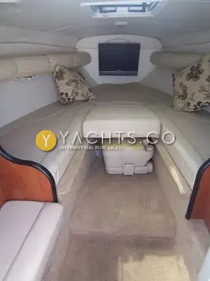Rinker 262: forward cabin with V-berth, cream upholstery, floral cushions, wall-mounted TV and portable toilet