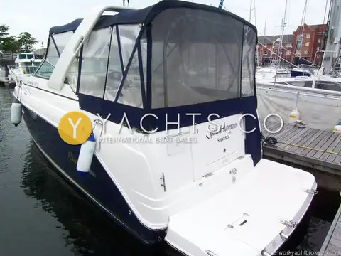 Rinker 270 Fiesta Vee: stern quarter showing full navy cockpit canopy, bathing platform and fenders at the pontoon