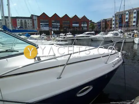 Rinker 270 Fiesta Vee: foredeck with stainless guardrail and deck hatch, marina buildings behind