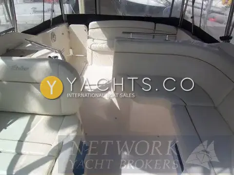 Rinker 270 Reduced: cockpit with cream wraparound seating and helm seat under the canopy