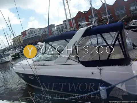 Rinker 270 Reduced: port side view at the marina berth, navy hull and full canopy fitted