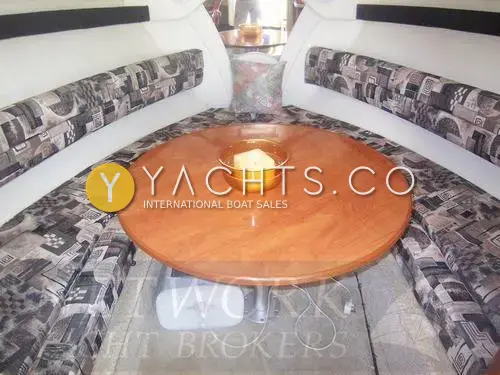 Rinker 270 Reduced: forward saloon with patterned U-shaped seating around a round cherry wood table