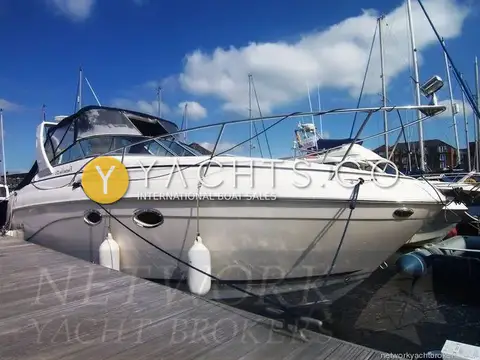 Rinker 270 Reduced: white hull and blue canopy, moored alongside a pontoon in a marina on a sunny day