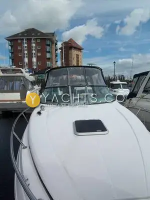 Rinker 280: foredeck with forward hatch and windscreen, marina apartment blocks behind