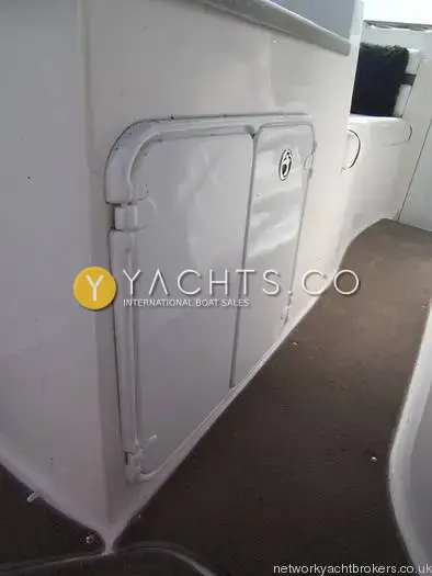 Rinker 280: cockpit side storage hatch with white door and brown carpet