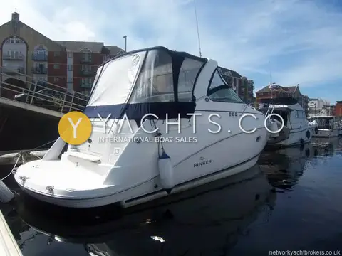 Rinker 330: port side and stern with navy cockpit canopy, moored beside a quayside walkway