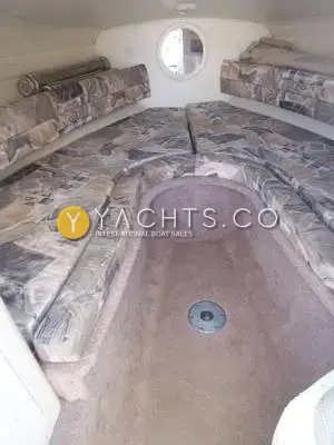 Rinker 232: forward cabin with patterned upholstered V-berth seating around a carpeted footwell