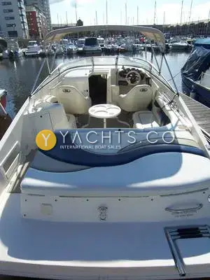 Rinker 232: cockpit seen from the stern, with sunpad, pedestal table, helm seats and bimini