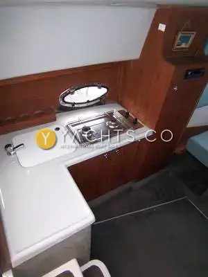 Rio 28: l-shaped galley with two-burner hob, covered sink, wood cabinetry and oval port