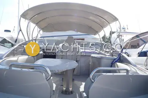 Riva Rivarama 44: cockpit under stainless bimini frame, with covered table, central helm seat and grey upholstery