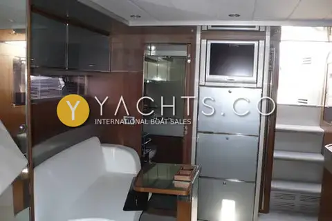 Riva Rivarama 44: saloon with white sofa, glass-topped table, wall-mounted television and steps up to cockpit