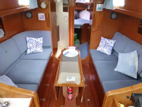 Rival 36: saloon with blue settees either side of central table, forward cabin beyond