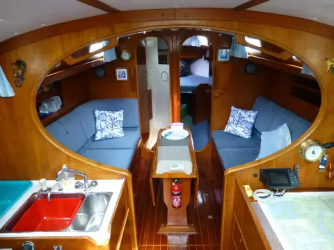 Rival 36: saloon looking forward through oval keyhole bulkhead, blue settees and drop-leaf table