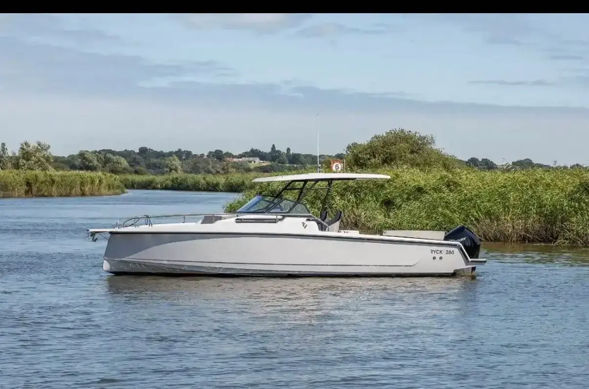 Ryck R280: white hull with T-Top and single black outboard, under way on a reed-lined river