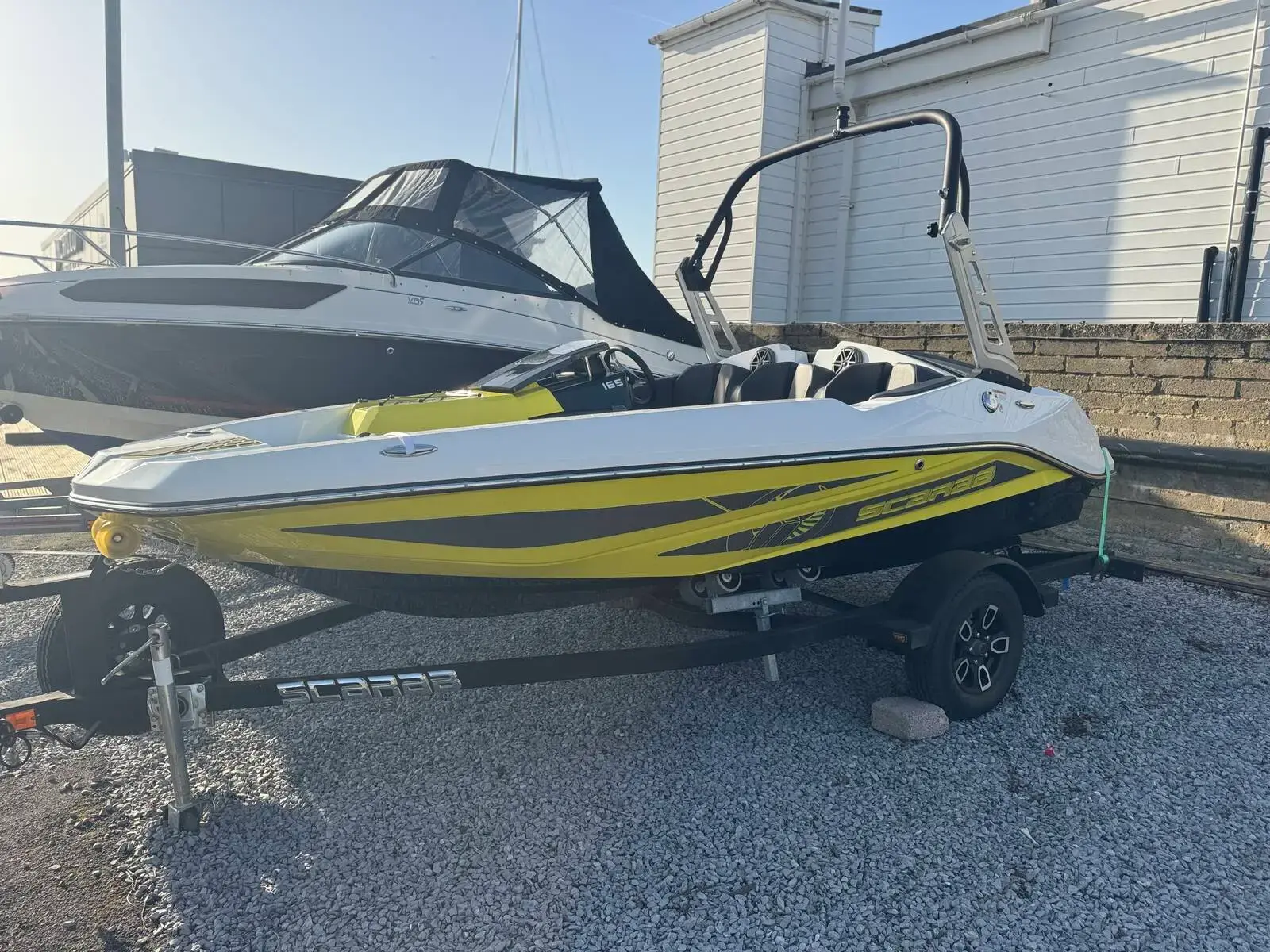 Scarab 165: port bow view of white and yellow jet boat with tower, on trailer in boatyard