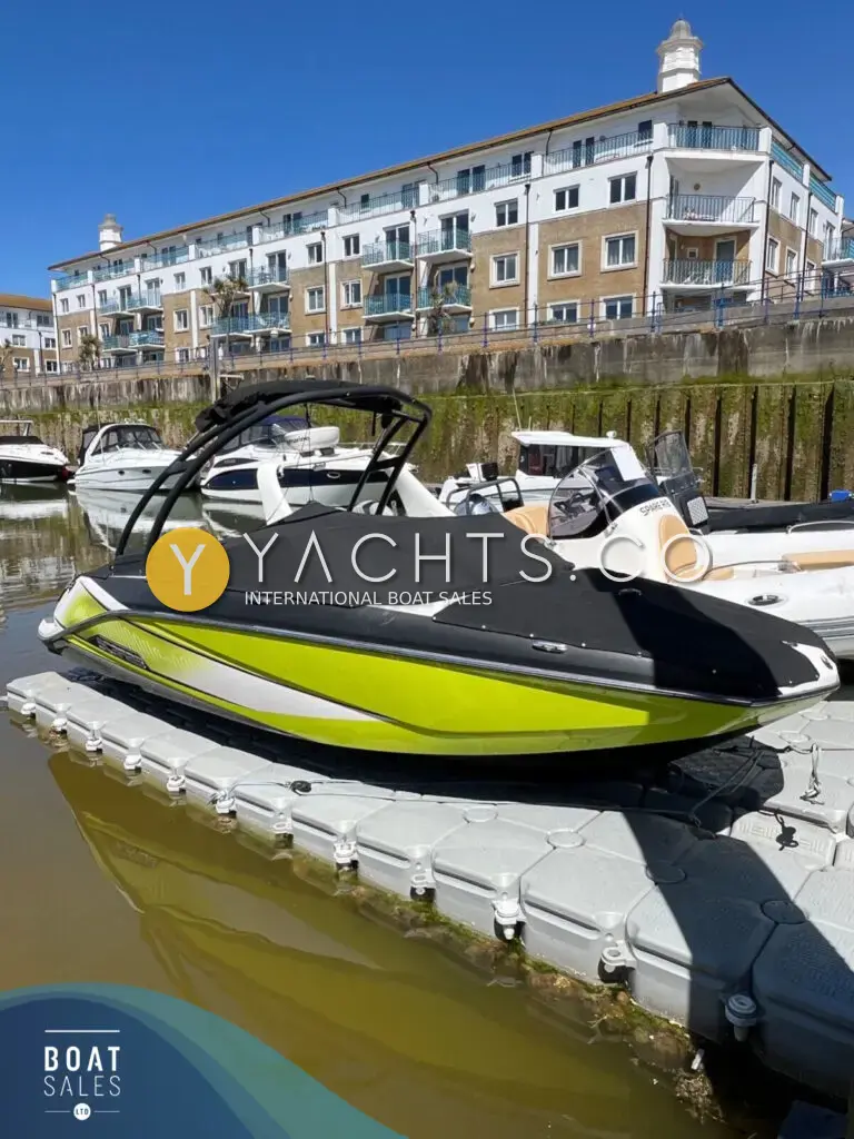 Scarab 195 ID: lime green and black hull with cockpit cover fitted, moored on a floating pontoon below flats