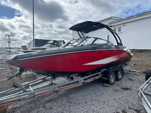 Scarab 215: port side view of the red hull with white graphics on a trailer in a boatyard