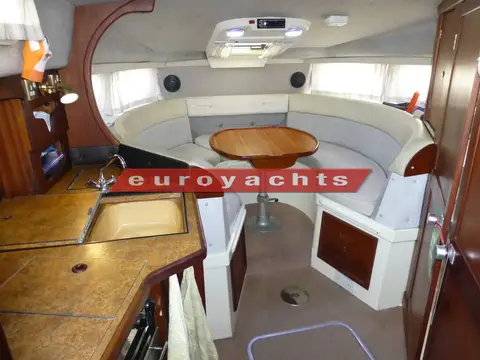 Sealine International 285: saloon with horseshoe seating, round wooden table and galley worktop to the left
